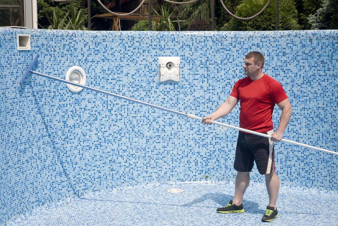 man cleaning the pool wall tiles